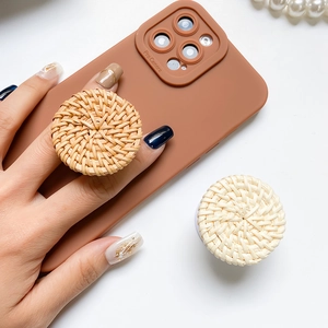 Detail of handmade rattan phone socket grip on a brown silicone case held by a model