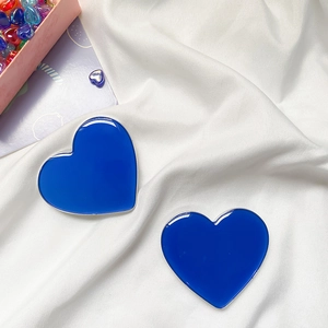 Blue heart-shaped metal phone grip pair on soft fabric with polished silver edges