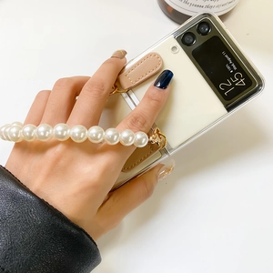 Detail of Galaxy Z Flip case featuring white pearl wrist strap and leather strap