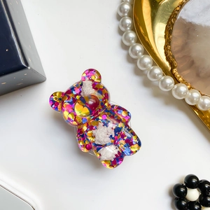 Dettaglio del supporto per telefono a orsetto con paillettes colorate e pompon bianchi