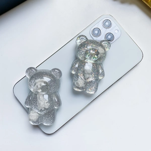 Macro detail of glitter bear phone grip with cloud patterns on white smartphone