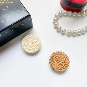 Detailed top view of handcrafted round woven rattan phone grips in natural wood and cream