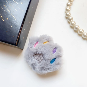 Detail of gray plush cat paw phone stand with colorful embroidery and star box