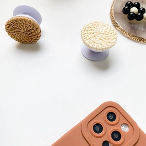 Detailed view of handmade woven phone sockets in dark brown and beige on white background