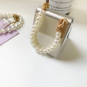 Detail view of pearlescent strap with golden lobster clasps on mirror phone case