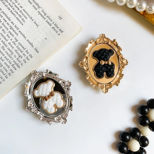 Detail of baroque gold and silver bear phone grips with lattice pattern on vintage book