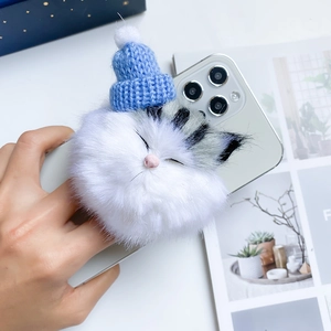Close-up of white plush cat phone socket with blue knit hat and grey stripe detail