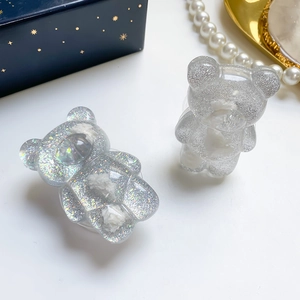 Detailed close-up of glittery resin bear phone grip with cloud accents on a tray