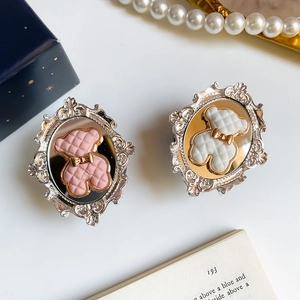 Detailed macro view of vintage baroque bear phone stands in pink and white finish