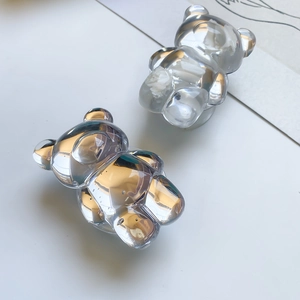 Macro detail of transparent bear-shaped phone grip with white floral resin texture