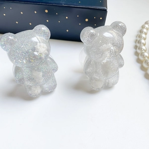 Macro shot of glittery resin bear phone grips with cloud effect and sequins