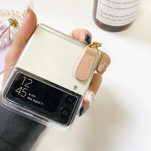 Close-up of clear Galaxy Z Flip case featuring pink leather charm and pearl strap