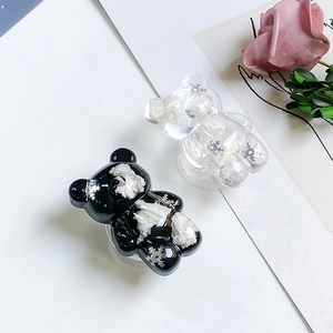 Close-up of bear-shaped phone socket grips with embedded white flowers and resin finish