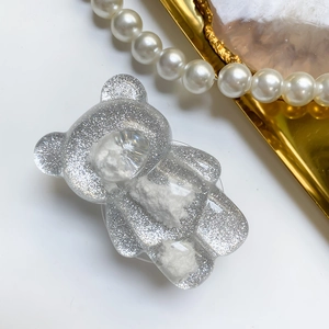 Close-up of sparkling silver glitter bear phone grip with white cloud-like textures