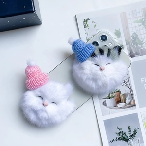 Detailed view of white plush cat phone grips featuring pink and blue mini knitted hats