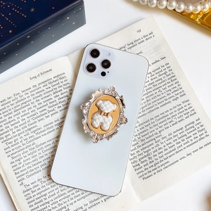 Close-up of vintage bear phone grip with gold embossed frame on a book background