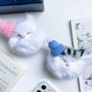 Detail view of plush cat phone sockets with cute knitted hats in white and grey colors