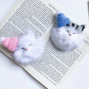 Close-up of cute plush cat phone holders with knitted hats on a vintage book page