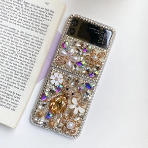 Detail of luxury rhinestone teddy bear and pearl flower charms on a folding phone case