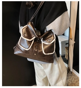 Detail of a dark brown large shoulder bag with white fleece trim and metal rivet pockets
