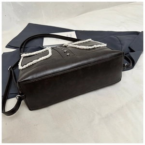 Detail of dark brown leather shoulder bag with white faux fur and silver rivet accents