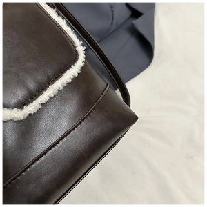 Close-up of brown faux leather handbag featuring white plush faux fur trim and stitching