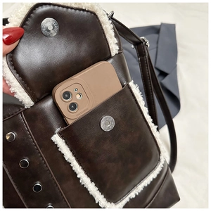 Detail showing plush trim messenger bag capacity with smartphone inside for scale