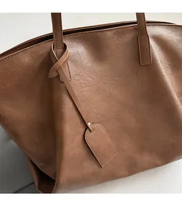 Close-up of brown faux leather tote bag showing vintage texture and stitching details