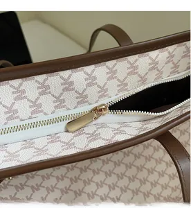 Close-up of smooth gold-tone zipper hardware on classic monogram printed tote bag