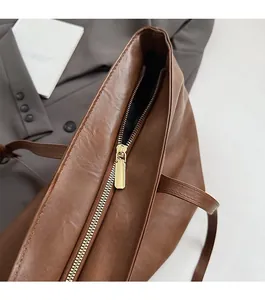 Close-up of golden metal zipper and brown leather texture on a spacious tote bag
