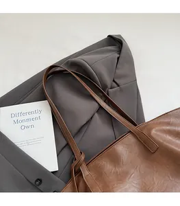 Detail of coffee brown tote bag featuring slender shoulder straps and textured faux leather