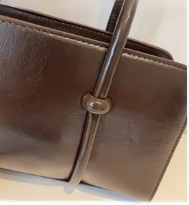 Détail macro de la texture en cuir marron foncé et de la boucle ronde sur le sac à main