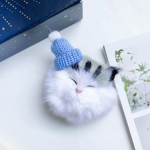 Cute plush cat phone socket with blue knit hat and pom-pom detail on aesthetic background