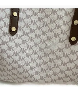 Macro detail of monogram leather tote bag featuring metal rivets and refined pebble texture