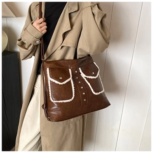 Detail of dark brown leather messenger bag with fleece-trimmed pockets on a khaki coat