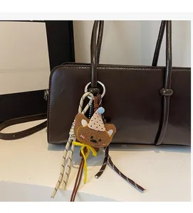 Gros plan d'un ours en peluche marron avec chapeau à pois sur un sac en cuir
