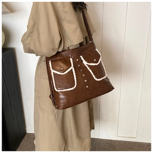 Detail view of large dark brown PU leather tote with sheepskin trim and dual front pockets