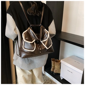 Detail of dark brown PU leather backpack with faux shearling trim and metal buckle straps
