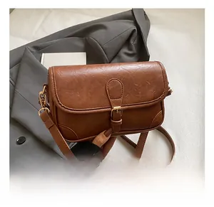 Close-up of brown vintage crossbody bag with gold buckle and textured faux leather finish