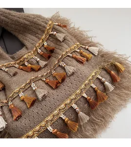Détail de pompons bohèmes et ruban tressé sur un sac fourre-tout en tricot marron