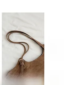 Detailed macro view of the brown suede tote bag featuring adjustable golden metal buckles