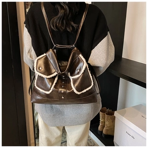 Detail of dark brown PU leather backpack with white faux fur trim and metal rivets