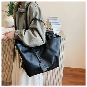 Macro side view of a large black faux leather tote bag with long double shoulder straps