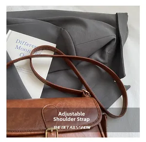 Detail showing high-quality lychee texture leather and golden metal buckle on brown bag