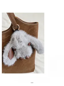 Detail of grey plush rabbit charm and brown leather handle on a large tote bag