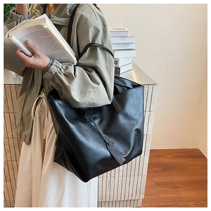 Detail of a large black vintage tote bag with leather texture shown on a female model