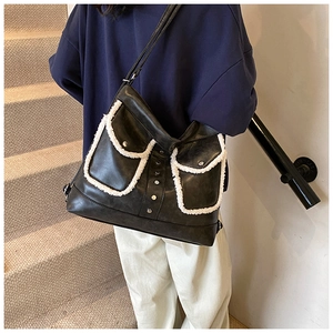 Detail of black leather tote bag featuring white faux fur trim and silver metal studs
