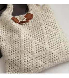 Detail of knit tote bag showing off-white texture and brown toggle button closure