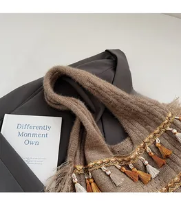 Détail d'un sac cabas en maille avec pompons et galons dorés sur un fond de tissu sombre