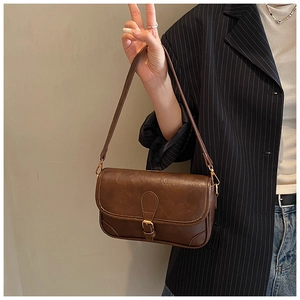 Detail of dark brown vintage PU leather texture and retro buckle on a small square bag